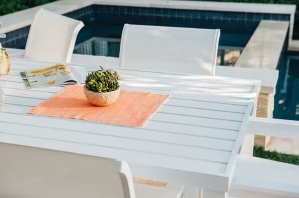 white table by the pool with a peach colored placemat and a plant white table by the pool with a peach colored placemat and a plant